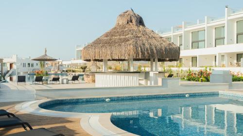 a swimming pool with a straw umbrella and a table and chairs at Mykonos Homes - Stilvolles Apartment mit eigenem Jaccuzzi in Bahçeli