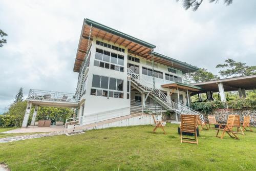 a white house with chairs in the yard at Majestic villa with stunning views in Jarabacoa in Buena Vista