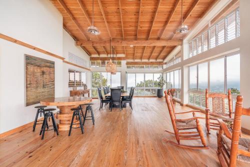 a dining room with a table and chairs and windows at Majestic villa with stunning views in Jarabacoa in Buena Vista
