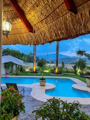 a resort with a swimming pool with a straw roof at VILLAS EL ENCANTO in Jalpan