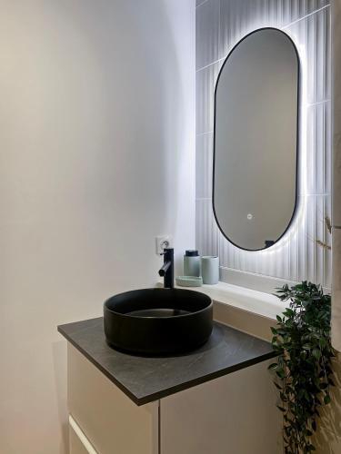 une salle de bain avec un lavabo noir et un miroir dans l'établissement LE NID VANNETAIS - Quartier historique et gare à pied, à Vannes