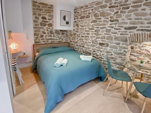 une chambre avec un lit bleu et un mur de briques dans l'établissement LE NID VANNETAIS - Quartier historique et gare à pied, à Vannes
