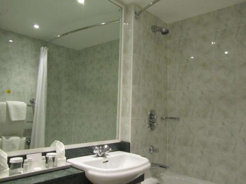 a bathroom with a sink and a shower with a mirror at Windmill Village Hotel, Golf Club & Spa, BW Signature Collection in Coventry