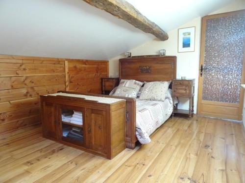 um quarto com uma cama e piso em madeira em La Bruyère aux Lamas em Saint-André-dʼApchon