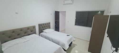 una camera da letto con due letti e una TV a schermo piatto di Jalehe a Juazeiro do Norte