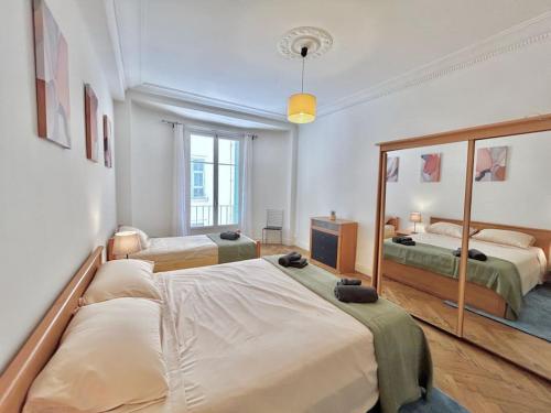 une chambre avec deux lits et un grand miroir dans l'établissement Charmant 3P en centre ville, spacieux et calme, à Nice