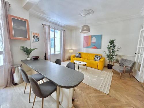 un salon avec une table et un canapé jaune dans l'établissement Charmant 3P en centre ville, spacieux et calme, à Nice