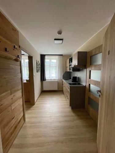 a kitchen with wooden floors and a hallway with a door at Apartmány U Bernharda in Vítkov