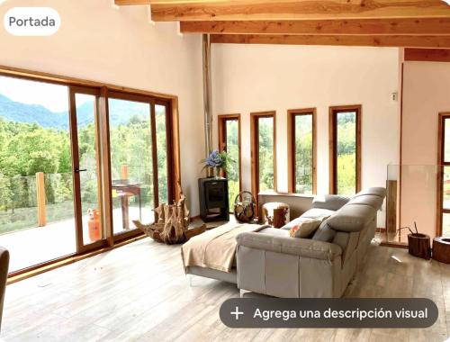 a living room with a couch and large windows at Casa en el bosque con hot tub in Pichare