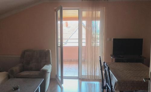 una sala de estar con una puerta corredera de cristal con una silla en Marija apartmani, en Kraljevo