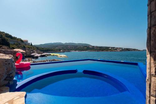 a large blue swimming pool next to a body of water at Vila Gloria in Bar
