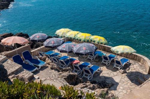 a group of chairs and umbrellas next to the water at Vila Gloria in Bar