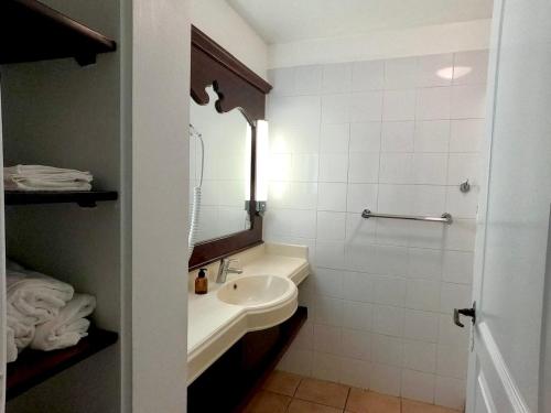a white bathroom with a sink and a mirror at Studio Zandoli P&V in Sainte-Luce