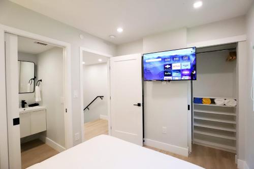 a white bedroom with a tv on the wall at Townhouse in Heart of South Beach Miami Steps to Sea in Miami Beach