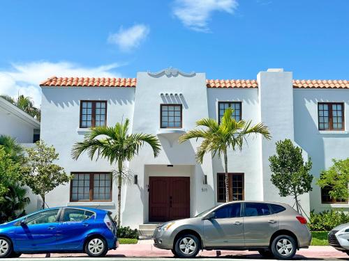 two cars parked in front of a white house at 6 Bedroom Villa with Pool & Parking in Heart of South Beach Miami in Miami Beach