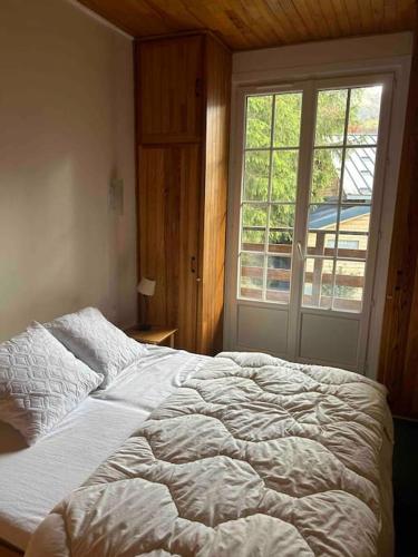 une chambre avec un grand lit avec une fenêtre dans l'établissement Grand Chalet pour 10 avec vue magnifique sur les pistes et les montagnes à 10mn à pied des pistes, à Eaux-Bonnes