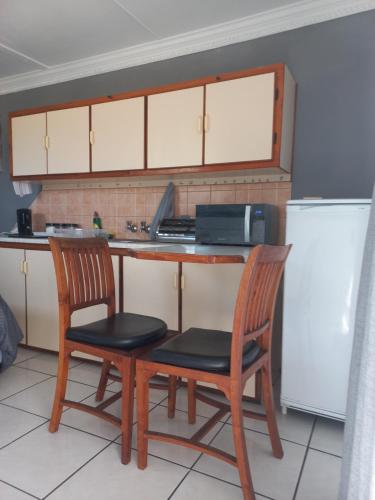 a kitchen with two chairs and a table and a refrigerator at Lion's Cave in Mossel Bay