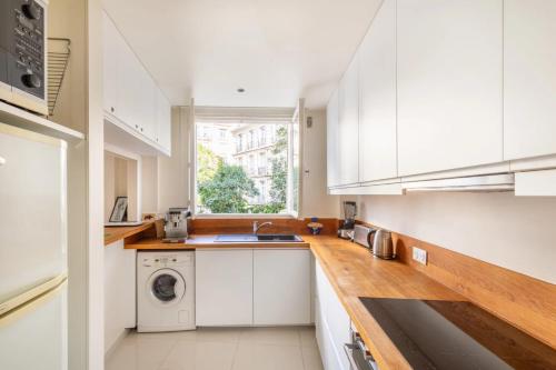une cuisine avec des armoires blanches et une laveuse et une sécheuse dans l'établissement Paris chic Trocadero, à Paris