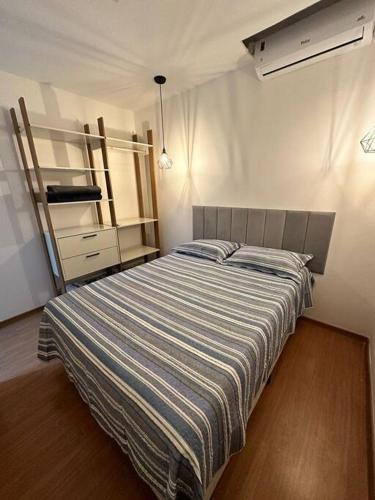 a bedroom with a bed with a striped blanket at 1204 Apto 2 Quartos Cabedelo Ponta de Campina Cabedelo TAXA DE ENERGIA E LIMPEZA SÃO COBRADAS NO CHECK-IN E CHECK-OUT in Cabedelo