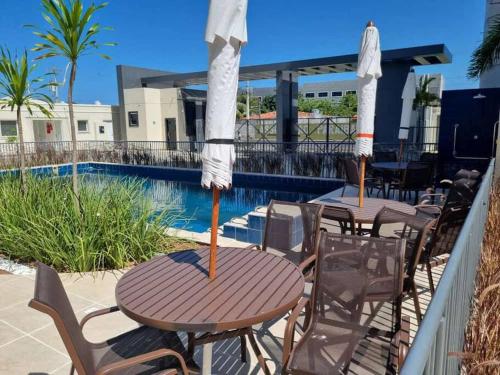 two tables with umbrellas on a balcony with a pool at 1204 Apto 2 Quartos Cabedelo Ponta de Campina Cabedelo TAXA DE ENERGIA E LIMPEZA SÃO COBRADAS NO CHECK-IN E CHECK-OUT in Cabedelo