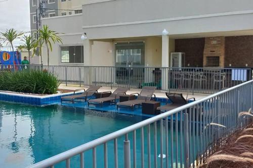 a swimming pool with chairs and water in front of a building at 1204 Apto 2 Quartos Cabedelo Ponta de Campina Cabedelo TAXA DE ENERGIA E LIMPEZA SÃO COBRADAS NO CHECK-IN E CHECK-OUT in Cabedelo