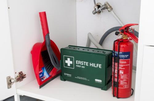 a red extinguisher and a green box on a shelf at Stay & Work Apartment Rheine in Rheine