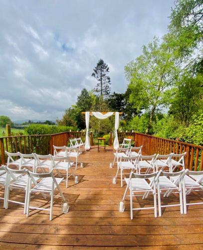 a bunch of white chairs on a wooden deck at Clone House Event Villa in Aughrim