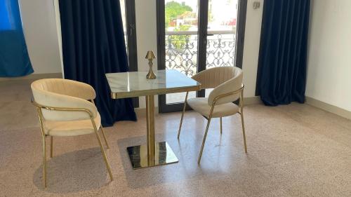 a glass table with two chairs and a statue on it at Arabian Nights Nook in Muscat