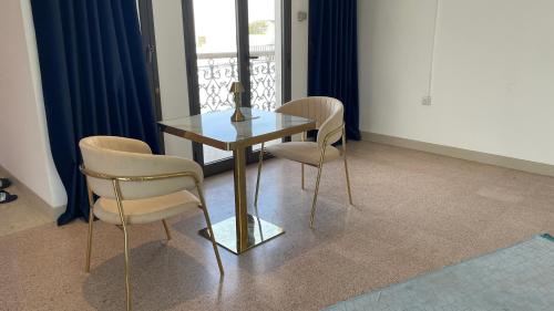 a dining room with a glass table and two chairs at Arabian Nights Nook in Muscat