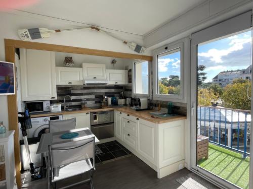 une cuisine avec des placards blancs et une vue sur un balcon. dans l'établissement Le Baulois, à La Baule