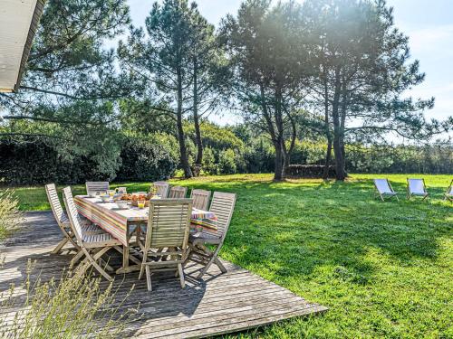 a table and chairs on a wooden deck in a yard at Holiday Home Le Prado-1 by Interhome in Saint-Philibert