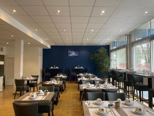 a restaurant with tables and chairs and a blue wall at The Originals City, Hôtel Villancourt, Grenoble Sud in Le Pont-de-Claix