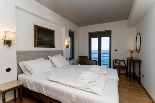 a bedroom with a white bed with a view of the ocean at LEONIDIONHOUSES - The Lykoskufi Villas in Tiros