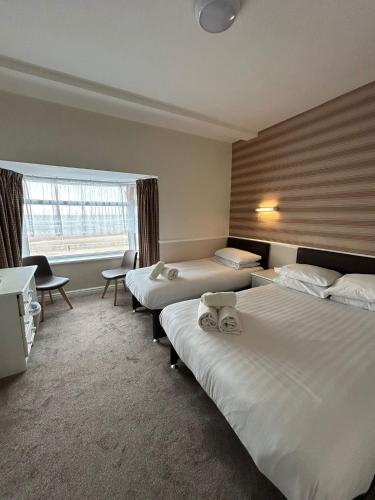 a hotel room with three beds and a window at Lyndene Hotel in Blackpool