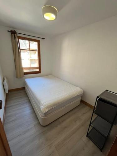 Un dormitorio pequeño con una cama y una ventana. en Luxueux T2 en centre ville, en Saint-Lary-Soulan