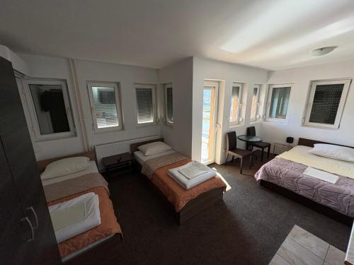 a bedroom with three beds and a table and chairs at Hotel Avanti in Zenica