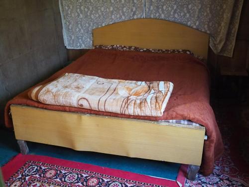 a small bed with a wooden headboard with at Veena Palace Group Of Houseboats in Srinagar