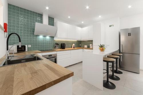 a kitchen with white cabinets and a stainless steel refrigerator at Surf & Chill Peniche Villa in Atouguia da Baleia