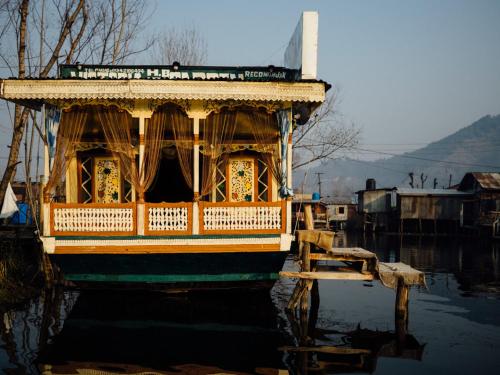 a boat sitting in the water next to a dock at Veena Palace Group Of Houseboats in Srinagar