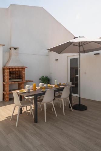 a dining room with a table with chairs and an umbrella at Surf & Chill Peniche Villa in Atouguia da Baleia