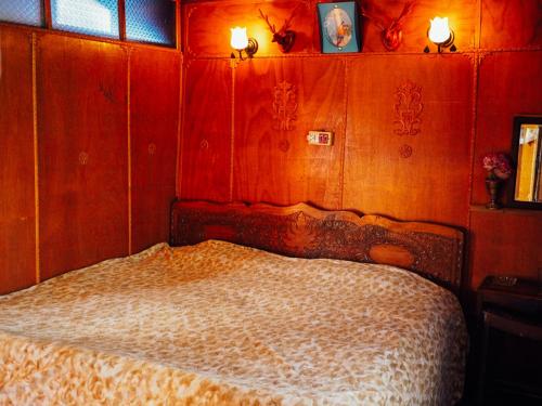 a bedroom with a bed with wooden walls and lights at Veena Palace Group Of Houseboats in Srinagar