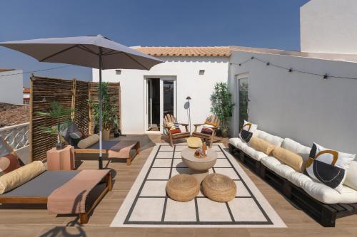 a patio with couches and tables and an umbrella at Surf & Chill Peniche Villa in Atouguia da Baleia