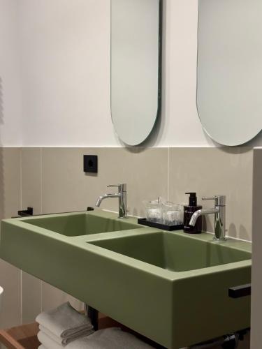 a green sink in a bathroom with two mirrors at OMÍ Aparthotel in Caserta