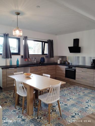 a kitchen with a wooden table and white chairs at Gite de la salamandre in Pléguien