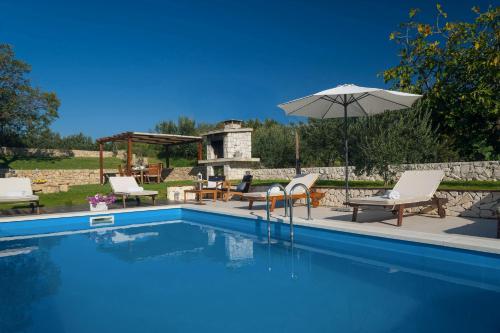a swimming pool with chairs and an umbrella at Luxury Villa Luminosa in Split