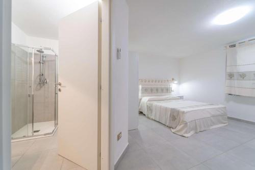 Habitación blanca con cama y ducha en La Stampa Home, en Olbia