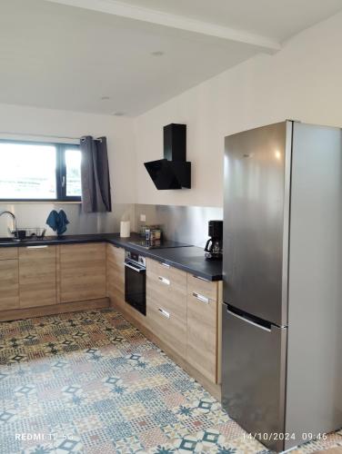 a kitchen with a stainless steel refrigerator and wooden cabinets at Gite de la salamandre in Pléguien