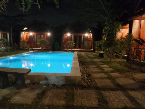 a swimming pool in front of a house at night at Awang Bungalows And Restaurants in Awang