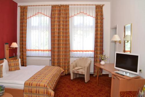 a hotel room with a bed and a desk and a television at Parkhotel Helene in Bad Elster