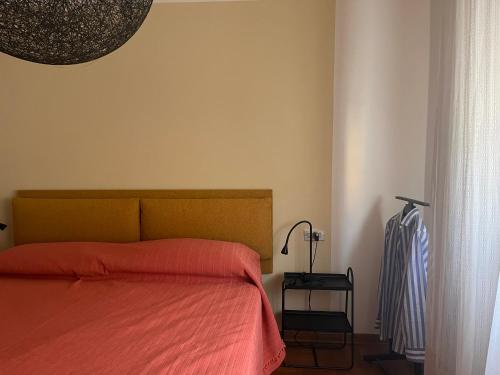 a bedroom with a bed with orange sheets and a lamp at Da' mi' nonni in Pistoia